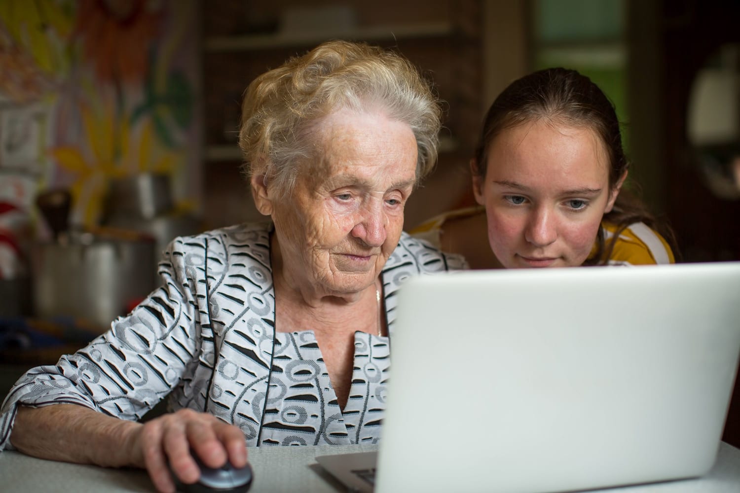 Older person with a young person looking at a laptop